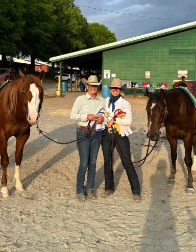 two girls holding awards with their horses